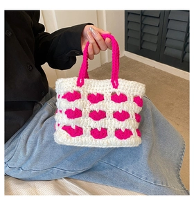 Dettaglio di una borsa all'uncinetto bianca con motivi a cuore rosa vivace e manico