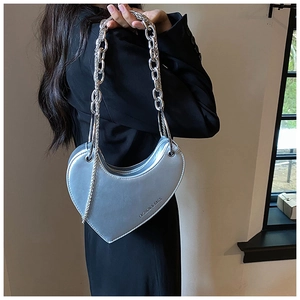 Détail du sac à bandoulière argenté en forme de cœur avec grosse chaîne métallique