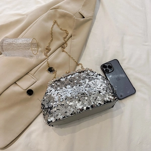 Vintage silver sequined evening clutch bag with gold chain strap on beige blazer backdrop
