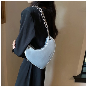 Sac à bandoulière argenté en forme de cœur avec chaîne épaisse sur un mannequin en costume