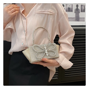 Close-up of sparkling silver evening bag featuring rhinestone bow and metal handle