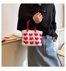 Dettaglio di borsa a mano all'uncinetto con base bianca e motivi rosa in rilievo