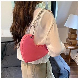 Détail du sac rose en forme de cœur avec chaîne argentée et lettrage décoratif
