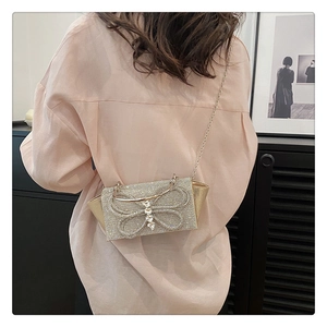 Detail of champagne gold evening bag with rhinestone bow worn over the shoulder