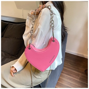 Détail du sac rose en forme de cœur avec chaînes argentées et logo imprimé