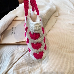 Dettaglio della trama a maglia di una borsa fatta a mano con cuori rosa e manico robusto