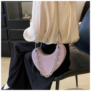 Détail d'un sac à main lavande en forme de cœur avec chaîne argentée et poignée ronde