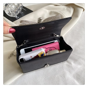 Detail of black satin evening bag interior with rhinestone bow and silver chain strap