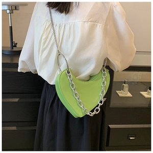 Gros plan du sac en similicuir vert clair en forme de cœur avec chaînes en argent