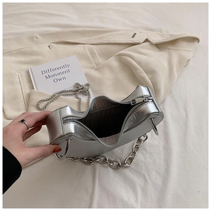 Gros plan détaillé d'un sac demi-lune argenté avec chaîne en métal et fermeture éclair