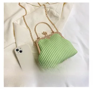 Detailed view of light green pleated evening bag with gold metal frame and phone for scale