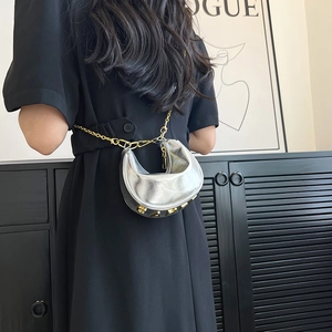 Silver metallic crescent bag with golden chain shown as a stylish waist bag on model