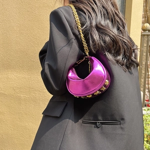 Metallic purple crescent shoulder bag with gold chain strap shown on a black suit model