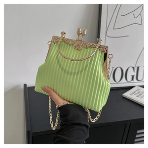 Detail of light green pleated handbag with vintage floral clasp and gold ring handle
