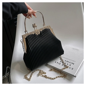 Detail of black pleated crossbody bag with gold metal frame and floral embossed clasp