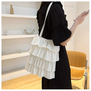 Seitenansicht einer weißen, gestuften Tragetasche mit Rüschen, getragen zum schwarzen Kleid.