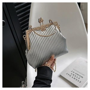 Detail of silver pleated evening clutch with gold floral clasp and metal chain strap