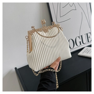 Detail of white pleated vintage handbag with golden floral engraved metal frame and handle