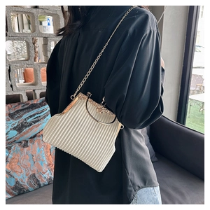 Close-up of cream evening bag featuring vertical pleats and floral metal clasp