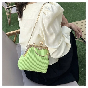 Macro detail of mint green pleated handbag with vintage gold clasp and round metal handle