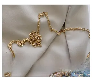 Close-up of light gold metal chain and floral rhinestone detail on sequined evening bag