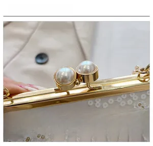 Detail of white evening clutch featuring gold frame, pearl clasp and floral embroidery