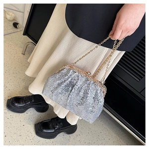 Detailed close-up of a sparkling silver sequin clutch bag with golden metal chain