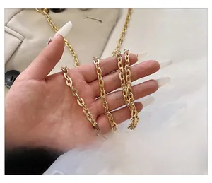 Detail of a golden metallic flat link chain strap on a stylish shoulder bag