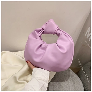 Detail of purple knotted handle handbag with pleated texture in a cafe setting