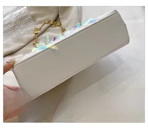 Detailed macro view of the stitching and iridescent leaf sequins on white leather bag base