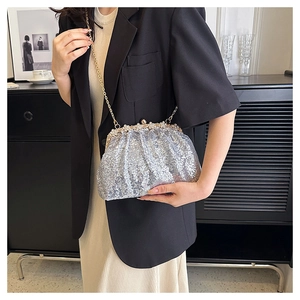 Close-up of sparkling silver sequin evening bag with elegant pearl and gold clasp detail