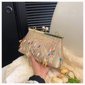 Close-up of champagne sequins evening bag with pearl clasp and colorful feather fringe