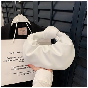 Detail of soft white pleated cloud bag showing the iconic knotted handle and faux leather texture