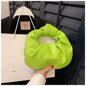 Close-up of vibrant neon green cloud bag featuring a signature knotted handle and ruched texture