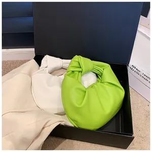 Detail of green and white mini hobo bags with knotted handles in a gift box