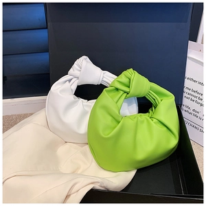 Detail view of the knotted handles and pleated texture on white and green handbags