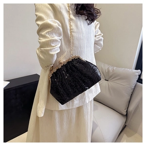 Close-up of black sequin evening clutch with gold rhinestone closure and pearl clasp