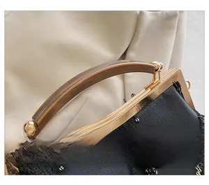 Detail of evening clutch with black sequins, gold metal frame and resin handle