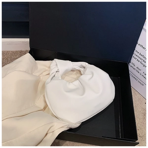 Detailed top view of white ruched leather knot handbag in a premium gift box
