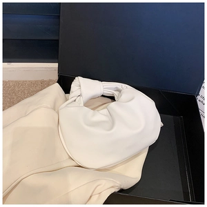 Detail of cream knotted handle cloud bag in a gift box with gathered PU leather texture