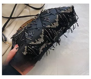Macro detail of black evening bag with gold sequin vine patterns and beaded fringe