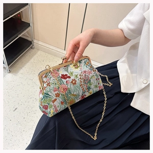Detail of vintage floral embroidery on crossbody bag with gold metal clasp frame