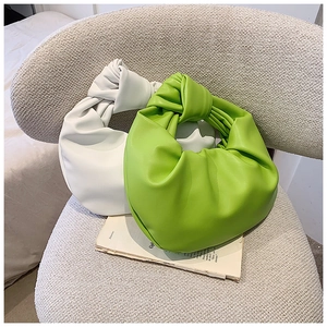Close-up of knotted handles and soft pleats on white and neon green cloud bags