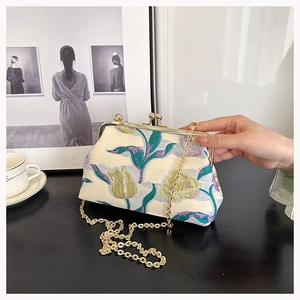 Detail of vintage floral jacquard fabric and antique golden clasp on the shoulder bag