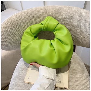 Detailed view of bright green knotted handle and pleated texture on hobo bag