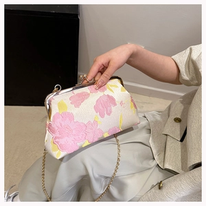 Detail of floral jacquard fabric and gold metal clasp on a vintage evening clutch bag