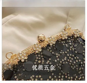 Détail d'un sac de soirée noir à paillettes avec un fermoir fleuri doré en strass