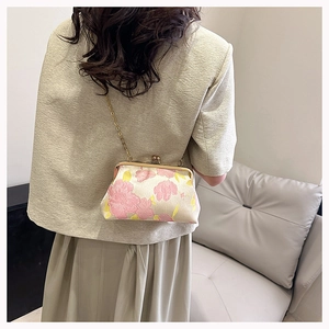 Detail of vintage floral jacquard clutch bag with gold metal clasp and chain strap