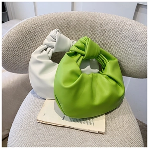 Detail of knotted handles and ruched texture on cream and green soft handbags
