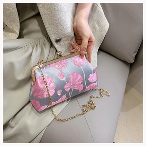 Close-up of vintage floral embroidery and golden metal clasp on a gray satin bag